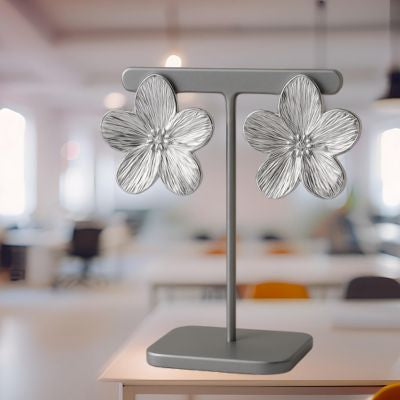 boucle d'oreille fleur argentée sur un présentoir gris foncé