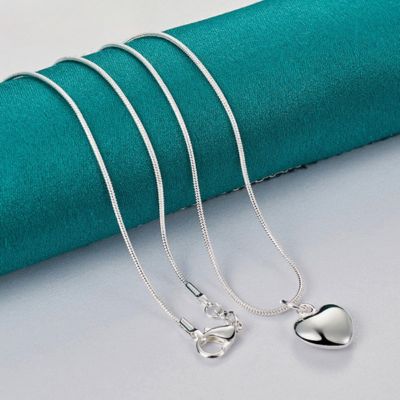 collier cœur argenté sur un présentoir vert