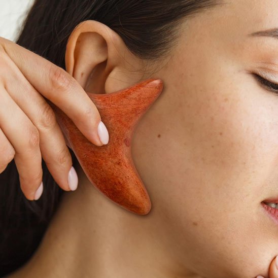 femme utilisant un gua sha pour masser le visage