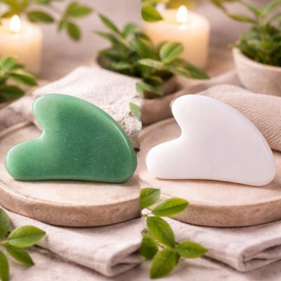 gua sha visage vert et ivoire sur plateaux en pierre