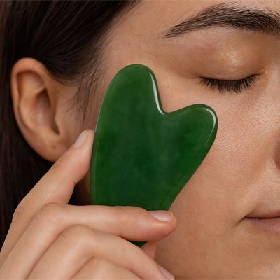 Pierre de gua sha vert femme relaxe les yeux fermés