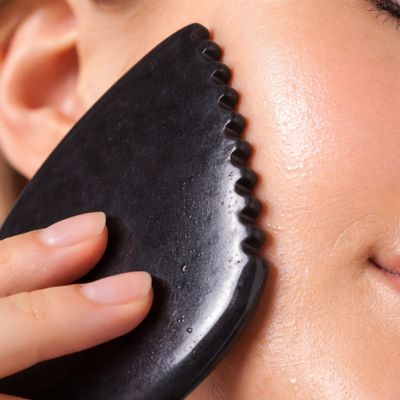 zoom sur dents pierre gua sha noir sur la peau